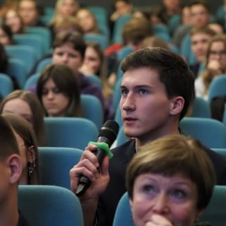 Jaunuolis su mikrofonu kino salėje klausia klausimo